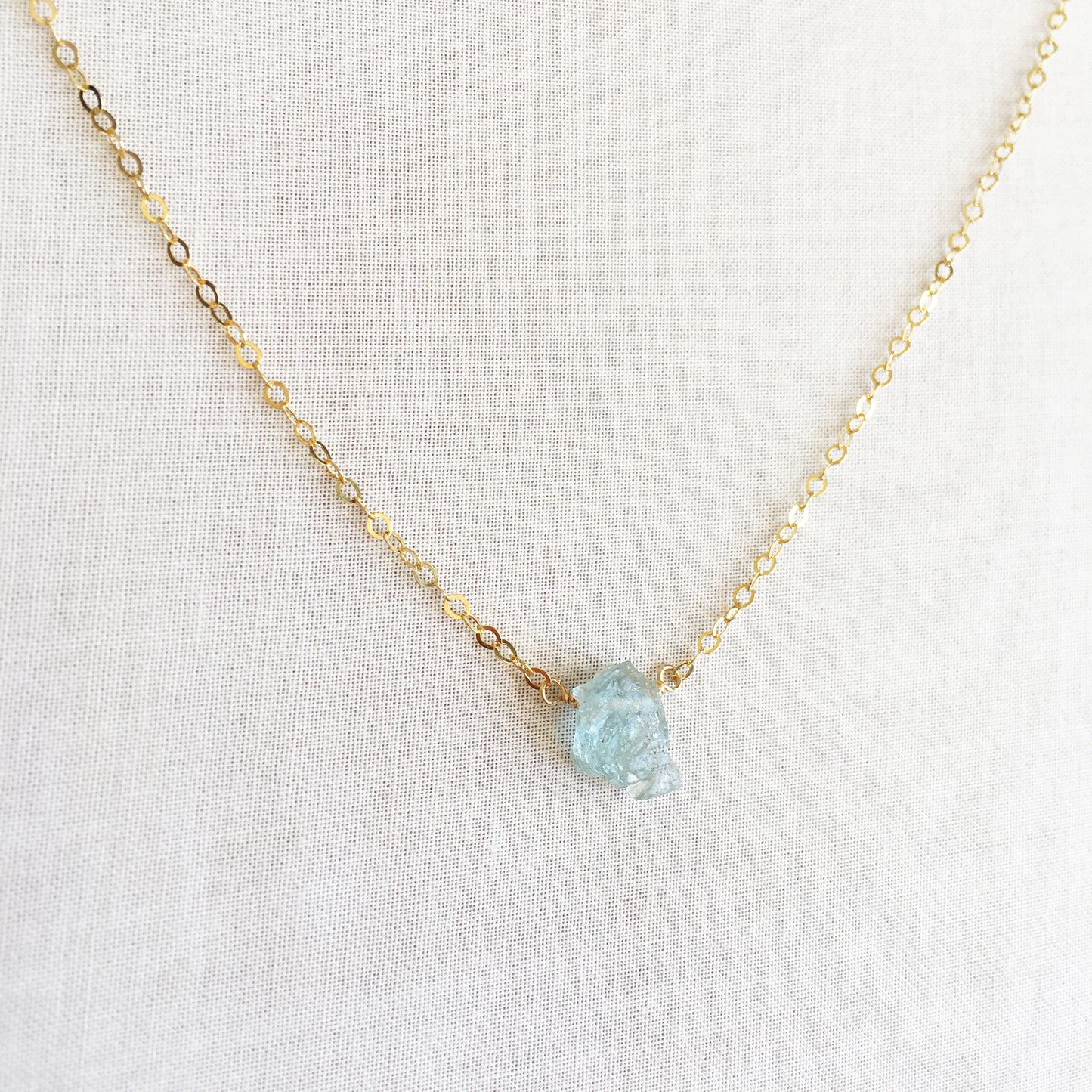 This is a Raw Aquamarine necklace that's made of 14k gold chain and raw Aquamarine.