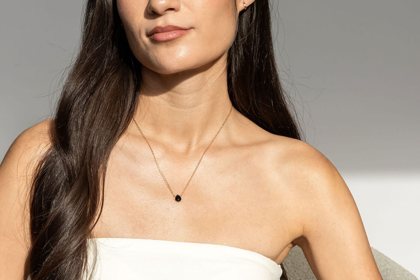 Model wearing a black tourmaline necklace with a 14k solid gold chain against a neutral background