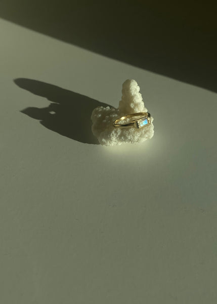 This is a gold moonstone ring that is setting in Baguette style. 