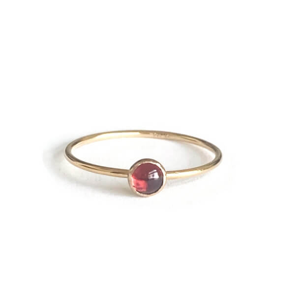 Gold ring with a red garnet on a thin gold band.