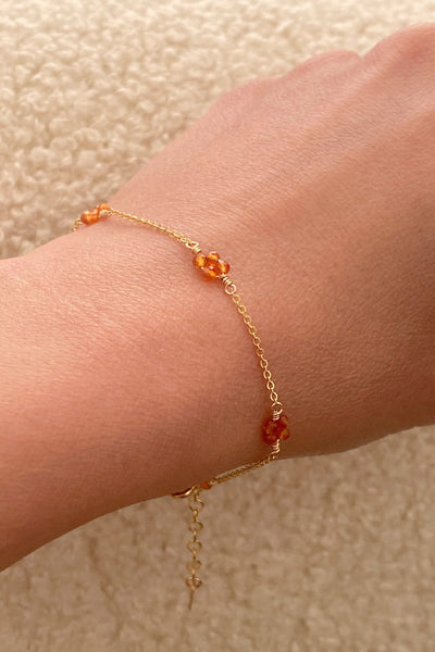 This is a dainty gold carnelian bracelet that has 4 flower beads around the bracelet. 