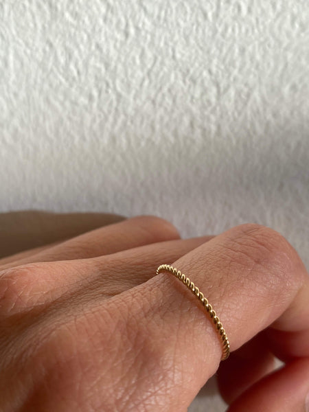 This is a person wearing a dainty gold twist ring that is made of gold filled wire.