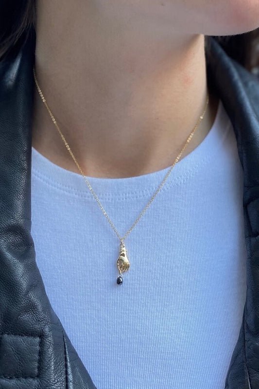 This is a gold pendant necklace featured genuine black diamond drop hanging off the hand charm. 