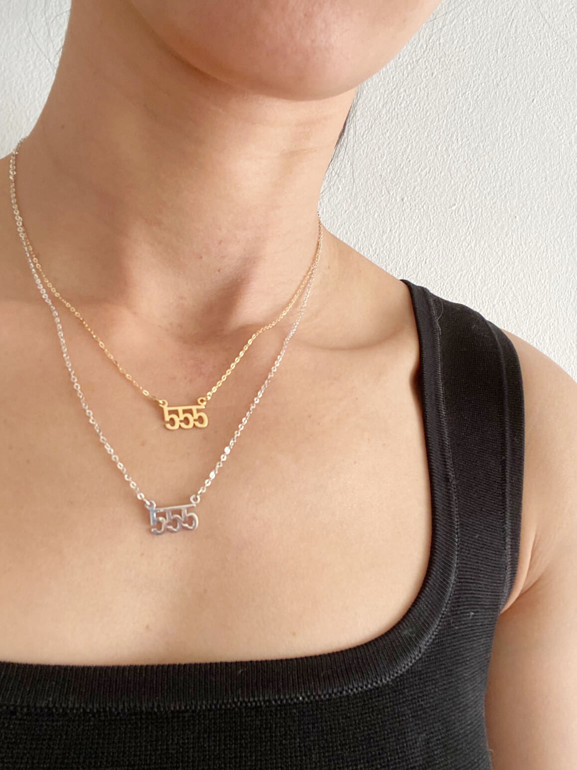 The model is wearing 2 of the 555 necklaces. The top one is a gold 555 angel number necklace that is 16" long. The lower one is a silver 555 angel number necklace that is 18" long.