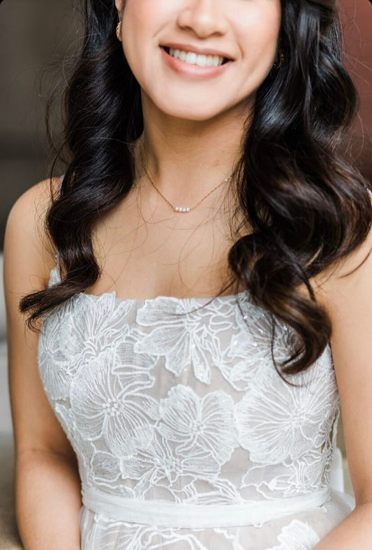 This is a gold pearl bead necklace. The bride is wearing it with her wedding dress. It's simple and dainty. Perfect for wedding day. 